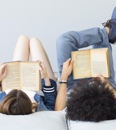 two young people reclining on pillows and reading books