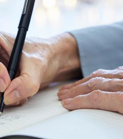 hands of elderly woman writing in a notebook