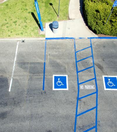 A photo of a parking lot featuring two spots for individuals with mobility disabilities. 
