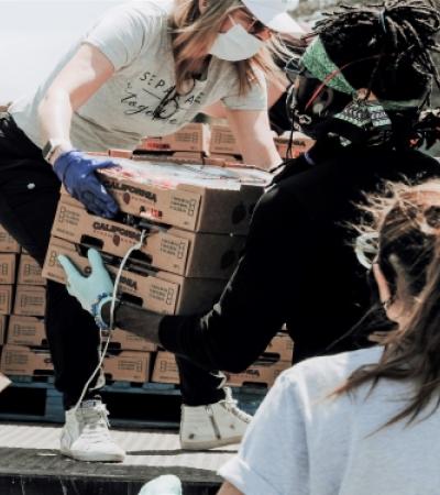 Photo of people passing boxes of food to each other.