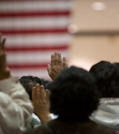 Photograph shows people at a swearing in ceremony for US citizenship.