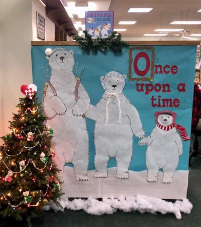 Photograph shows the indoor entrance to the StoryWalk. Image shows a large poster with three polar bears. Text on the poster reads "Once upon a time"