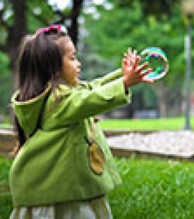 A young girl playing with bubbles in a park