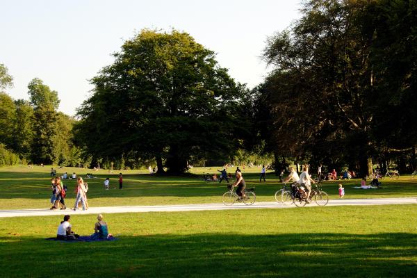 Photograph of a public park with people sitting, walking, and biking.