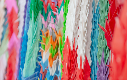 Photograph of strands of colorful paper cranes.