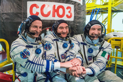 Three Expedition 60 astronauts sitting together in their space suits