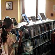 A girl stand between two bookshelves while playing laser tag in the library.