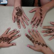 Four participants show off their hands with completed henna designs.