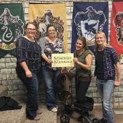 Four people pose with "Mischief Managed" sign
