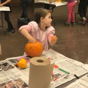 A girl pulling out pumpkin "guts"
