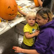 A child and woman carving a pumpkin together