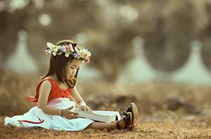 Little girl reading a book outside photo by MI PHAM on Unsplash