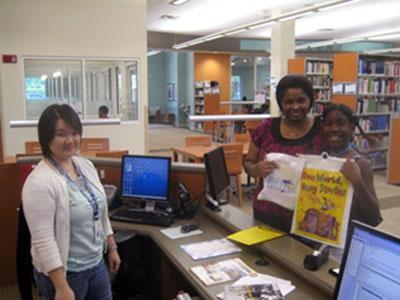 Wellington Branch librarian Cat Ng signs up a mother and daughter for Palm Beach County Library System’s adult and children summer reading programs.