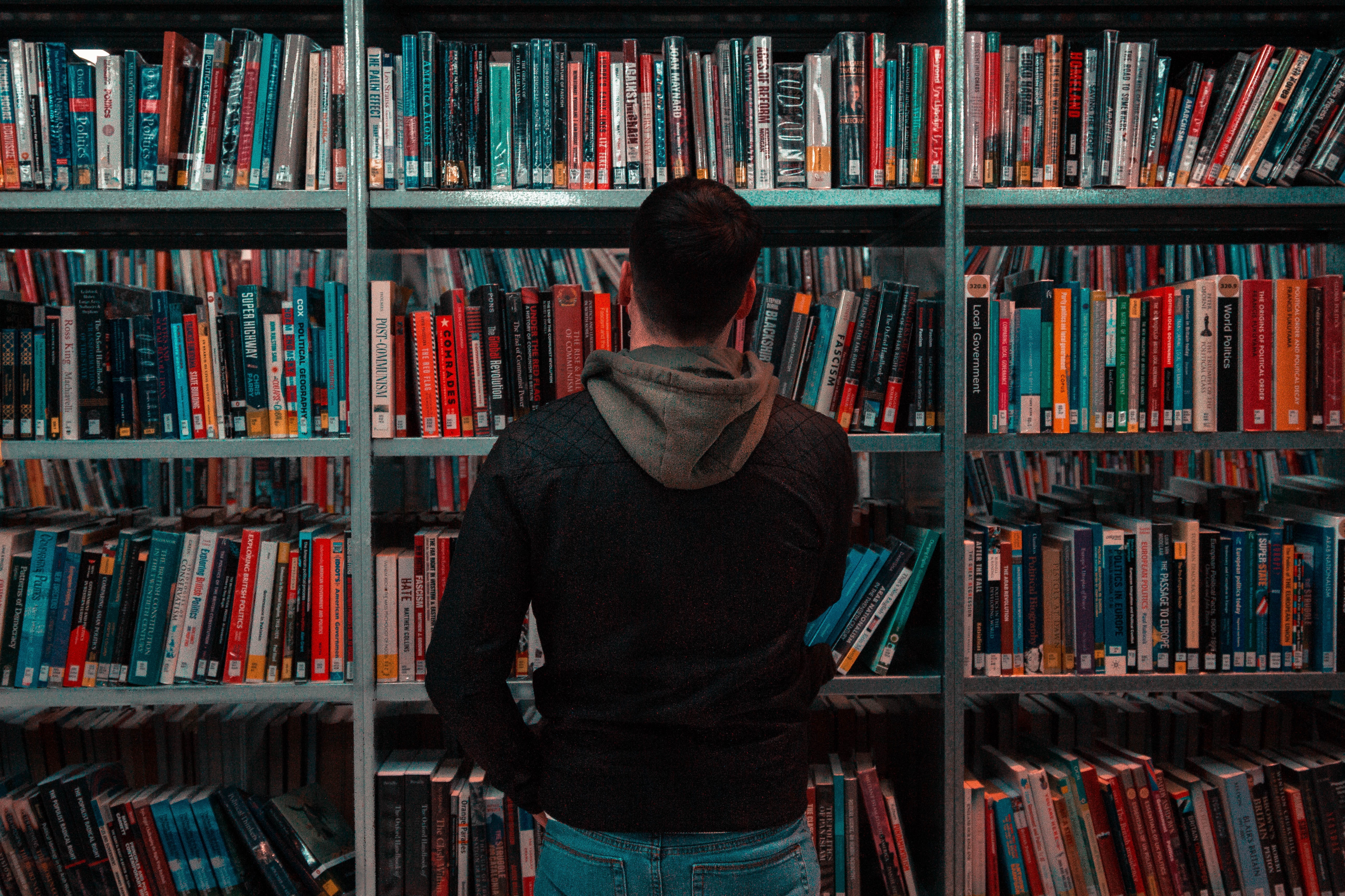 Photograph of a person with their back to the camera, facing a large bookshelf.