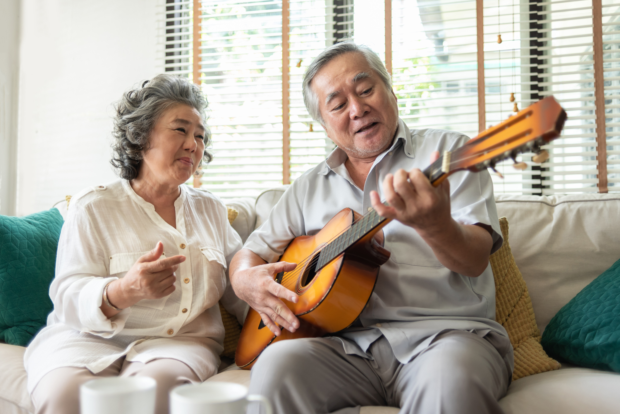 Photograph of senior couple playing guitar on a couch