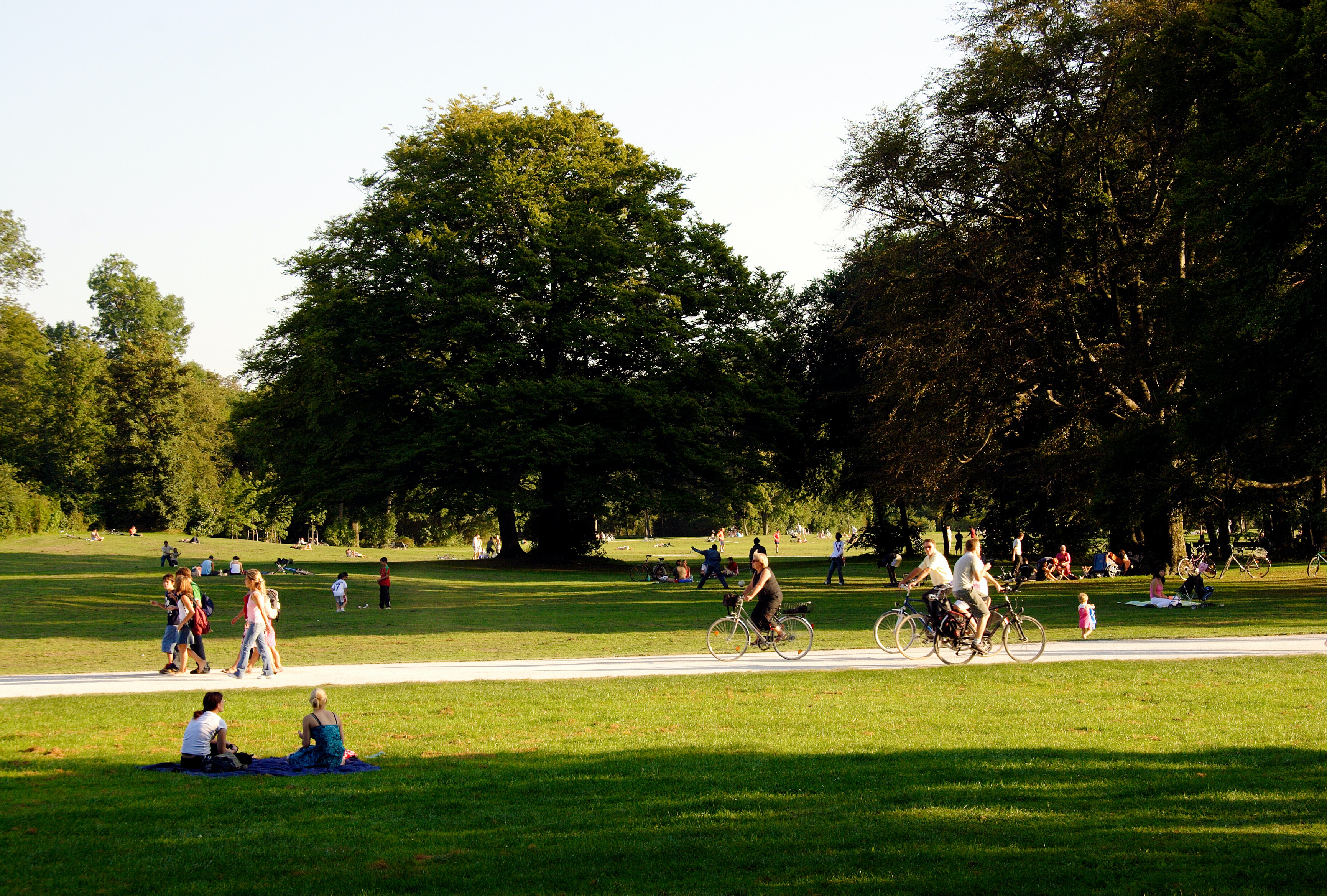 Photograph of a public park with people sitting, walking, and biking.