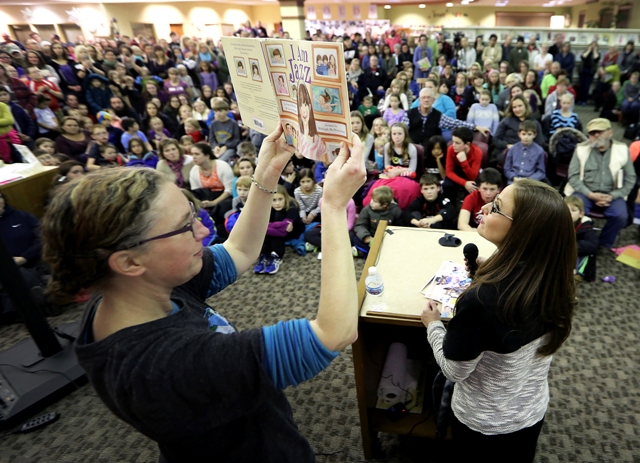 An art teacher from Madison, Wis., holds up a copy of "I Am Jazz" to the crowd as co-author Jessica Herthel reads aloud. 