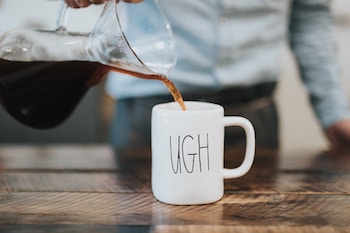 Pouring coffee into a mug that says "ugh"