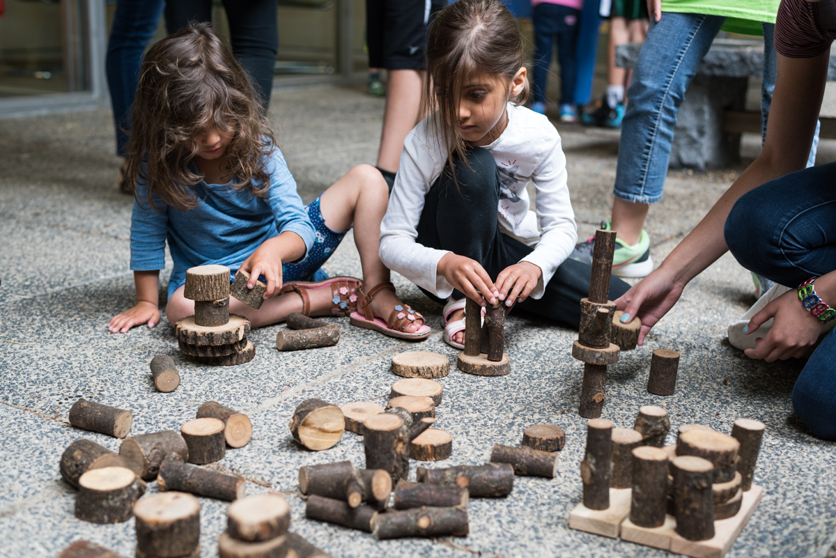 Children sitting on the ground, playing with Tree Blocks