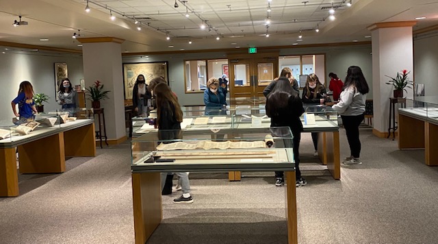 Photograph of people looking looking into glass exhibit cases.