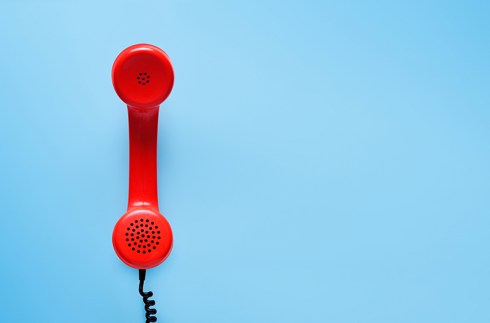 Photo of a red landline phone against solid blue background.