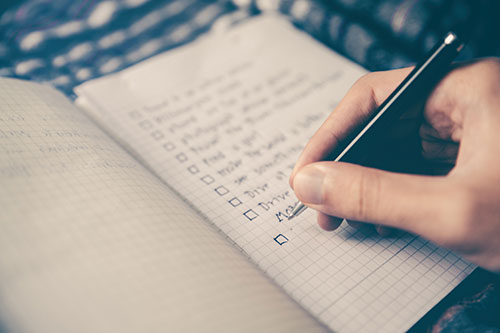 Hand checking off a to-do list in a notebook