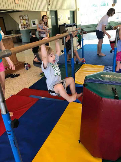 Young child hanging from a bar at a recreational facility