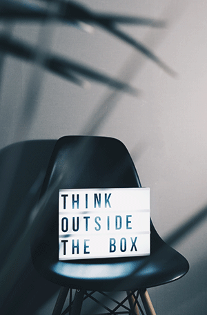 The words Think Outside the Box spelled out on a small letterboard sitting on a chair