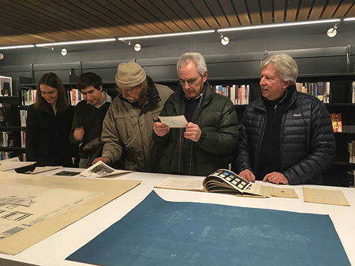 Group of people looking at paper artifacts around a table
