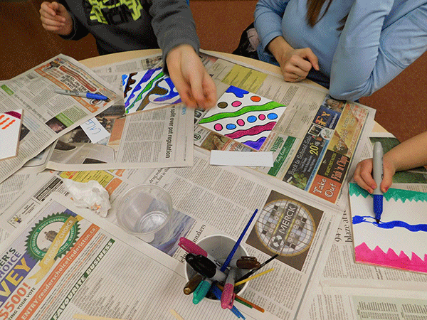 A group of program participants paint on their tiles