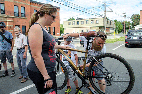 Man working on a bicycle while a woman looks on