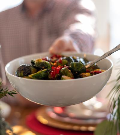passing a dish of brussels sprouts at a festive holiday table