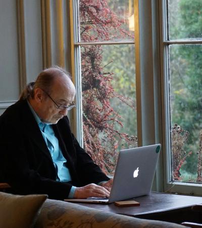 A person sits at a table using a laptop.