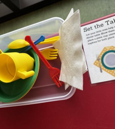 A photograph of the Set the Table station with napkins and plastic dishes.