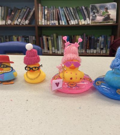 Four rubber ducks dressed up in small hats and other accessories.
