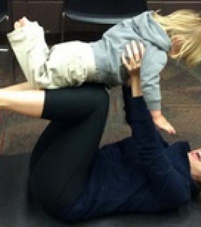 Woman holding toddler in airplane pose