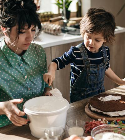 Photo of mother and child decorating a cake.