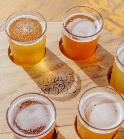 a flight of beers on a wooden tray