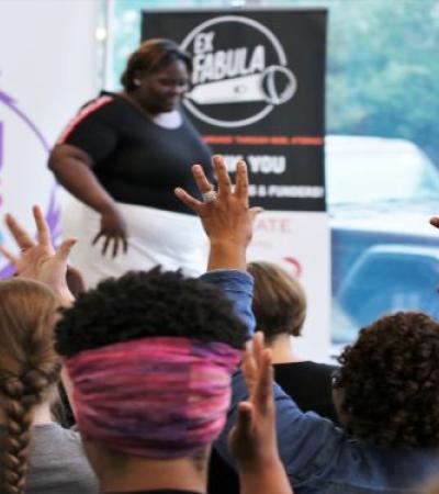 Photo of a person participating in Deaf Storyslam with audience members onlooking.