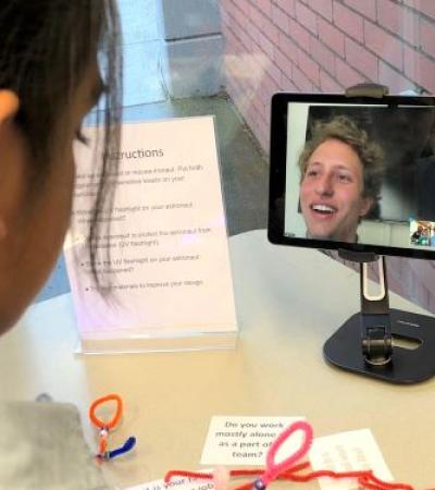 Photo of a child speaking with a scientist on a tablet.