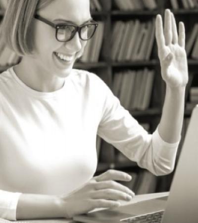Woman smiling and waving to laptop screen