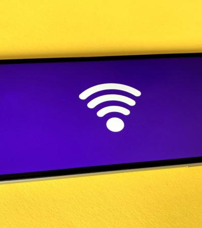 Photograph of iPhone with a wifi symbol on screen against a yellow background.