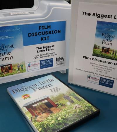 Photograph of a Film Discussion Kit for "The Biggest Little Farm." Photograph shows the DVD, Film Discussion Guide binder, and container.