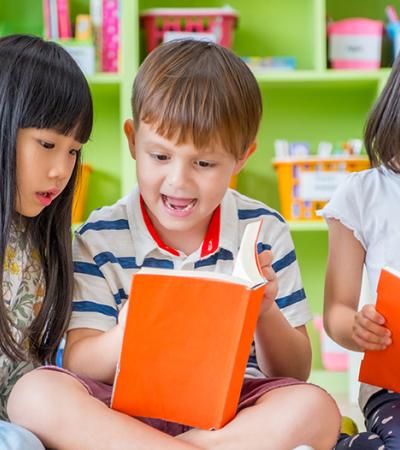 Three children sitting down and looking at books