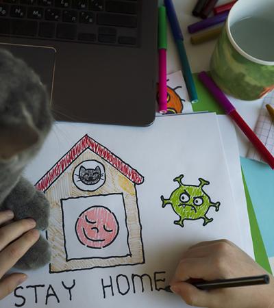 A photo of a child drawing a picture titled "Stay home"