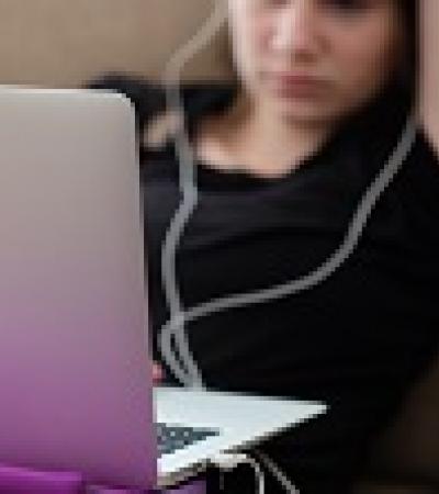 Teenage girl with headphones on looking at her laptop