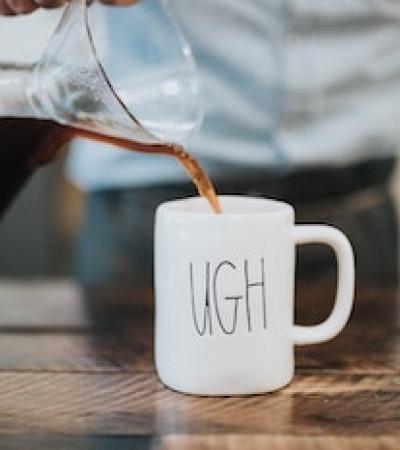 Pouring coffee into a mug that says "ugh"