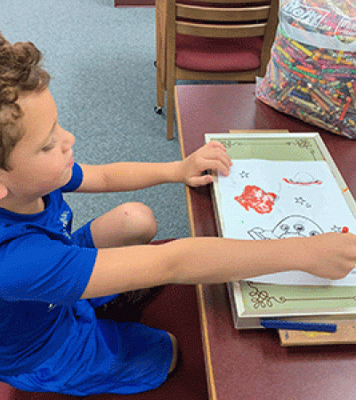 A young patron uses a hot plate to melt crayons while coloring at the Griswold Public Library.