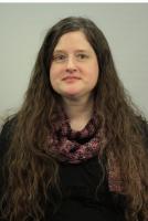 person with long hair looking at camera in black shirt and knitted scarf