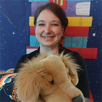 Tracy Guillorn holding a stuffed dog and smiling toward camera